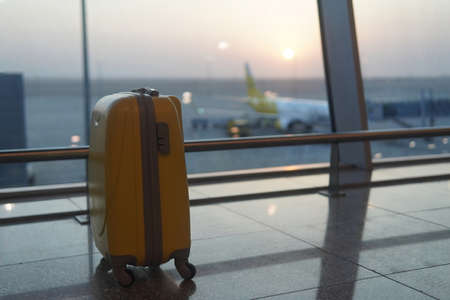 yellow suitcase standing at the airport for the background sunsetの写真素材