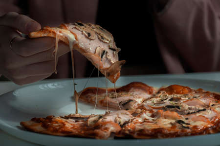 women's hand take a piece of pizza close-upの写真素材