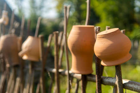 old clay pots hanging on a wooden fence of a branchの写真素材