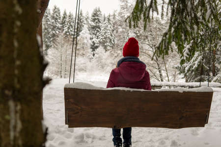 Girl sit on a swing in the winter forest. high qualityの写真素材
