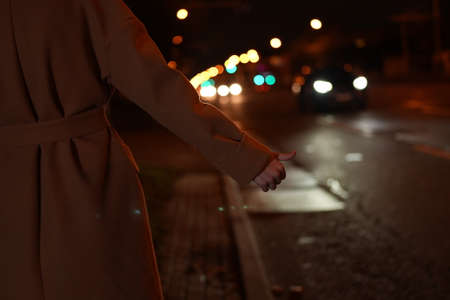 woman raise her hand to stop the car on the night road.