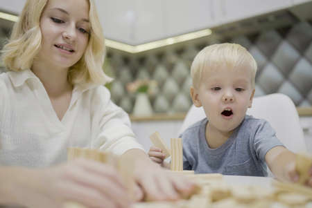 children playing tower to remove wooden blocks at home. two girls and boy having fun together - board game and kids leisure concept.の写真素材