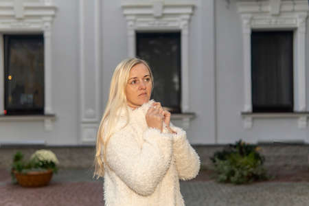 portrait of a blonde girl in a white fur coat in the city in autumn.の写真素材