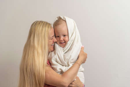 mom hold little son after bathing on light background.の写真素材