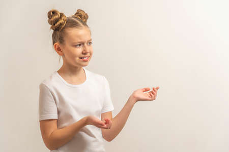 teenage girl with dark hair hair in a white t-shirt on a light background to be interested and think.の写真素材