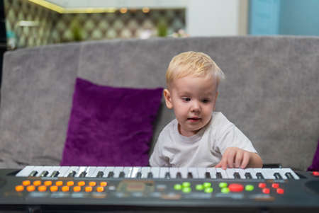 little boy learning to play the piano at homeの写真素材