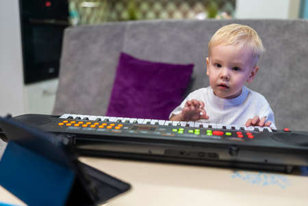 little boy learning to play the piano at homeの写真素材