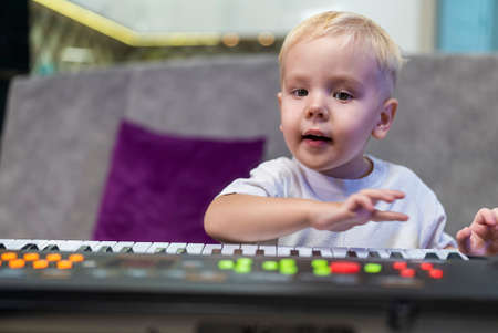 little boy learning to play the piano at homeの写真素材