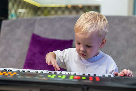 little boy learning to play the piano at homeの写真素材
