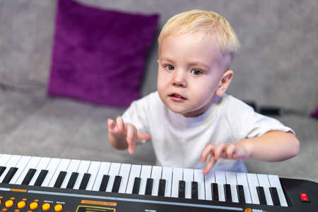 little boy learning to play the piano at homeの写真素材