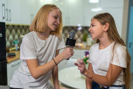 two teenage girls singing microphone at home funの写真素材