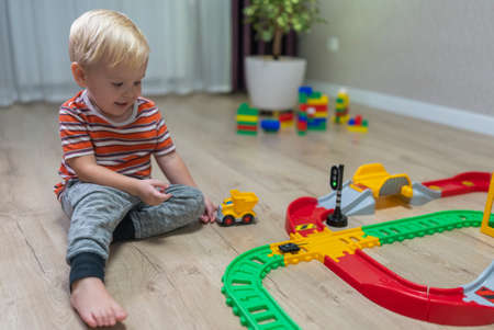 toddler blonde play railway in house on the floor.の写真素材