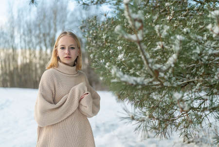 Portrait girl teenager blonde winter on the background of snow-covered trees.の写真素材