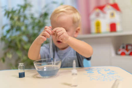 little boy child blonde play chemical experiments to sit at the table at homeの写真素材