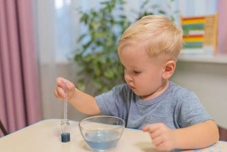 little boy child blonde play chemical experiments to sit at the table at homeの写真素材