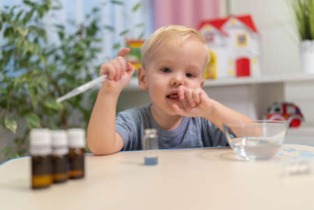 little boy child blonde play chemical experiments to sit at the table at homeの写真素材