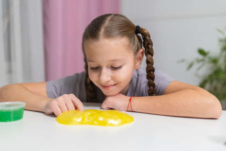 girl play with yellow slime at table fun at home.の写真素材