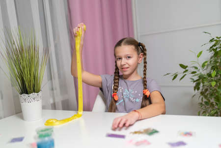 girl play with yellow slime stretch and fun at homeの写真素材