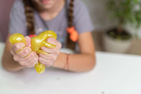 close-up girl play with yellow slime fun at home.