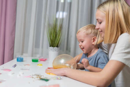 and little brother play with yellow slime at table fun at home sisterの写真素材