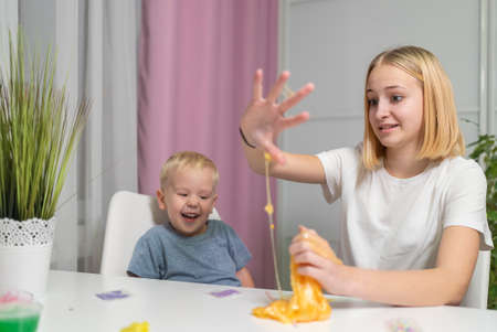 and little brother play with yellow slime at table fun at home sisterの写真素材