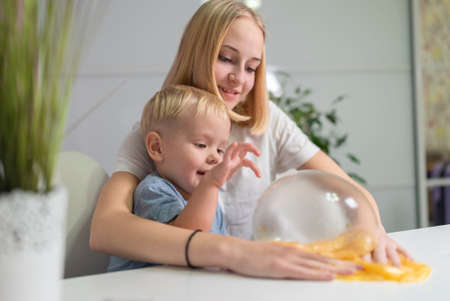 and little brother play with yellow slime at table fun at home sisterの写真素材