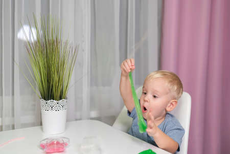 little boy play with yellow slime at table fun at home.の写真素材