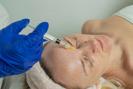 Close-up of a cropped image of a doctor's hands doing facial mesotherapy on a beautiful woman