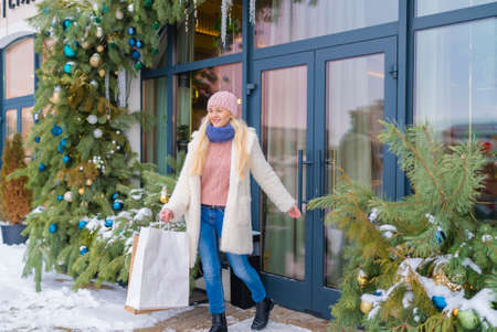 girl going out of the store with purchases on the background of Christmas fir. sale.の写真素材