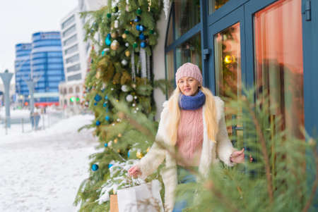 girl going out of the store with purchases on the background of Christmas fir. sale.