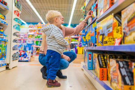 Mom chooses a gift from a toy store for her son.の写真素材