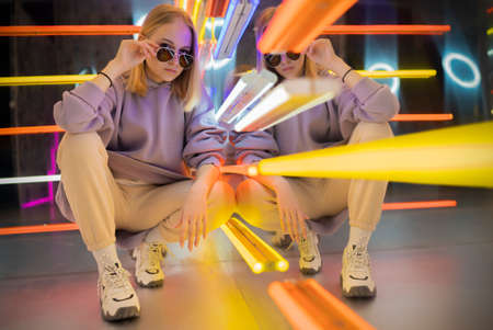 portrait of a stylish teenage girl in a neon room