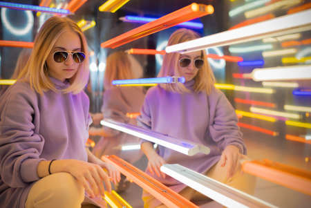 portrait of a stylish teenage girl in a neon roomの写真素材