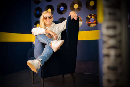 portrait stylish blonde girl on a blue chair.の写真素材