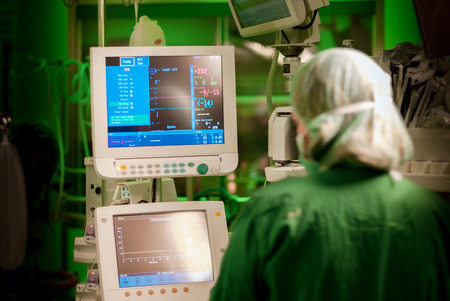female anaesthesiologist at monitor in operation surgery room with green lights onの写真素材