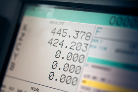CNC machine monitor display with program code running and numbers with parameters changing