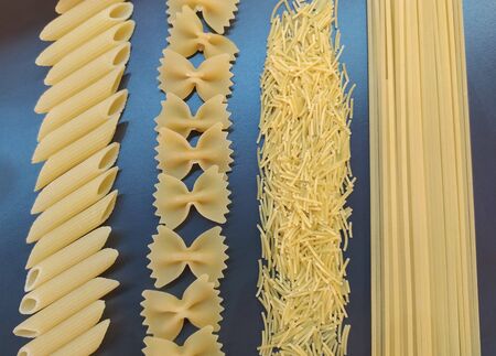 Background of pasta. Pasta on dark background. Different types of dry italian pasta on a gray background.の写真素材