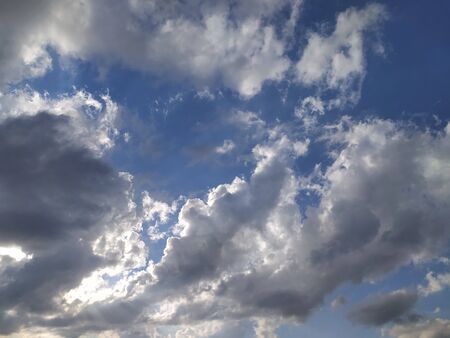 Blue sky with gray and white clouds at sunset, background, unstable changeable weather.の写真素材