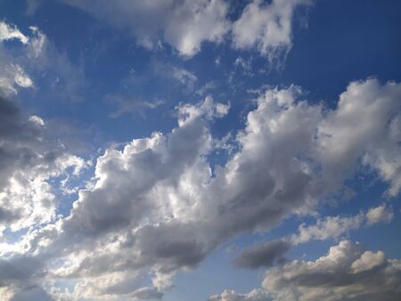 Blue sky with gray and white clouds at sunset, background, unstable changeable weather.の写真素材