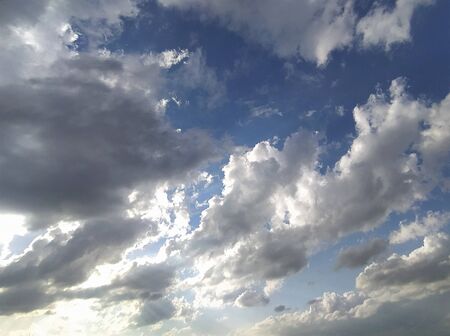 Blue sky with gray and white clouds at sunset, background, unstable changeable weather.の写真素材