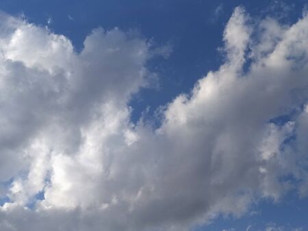 Blue sky with gray and white clouds at sunset, background, unstable changeable weather.
