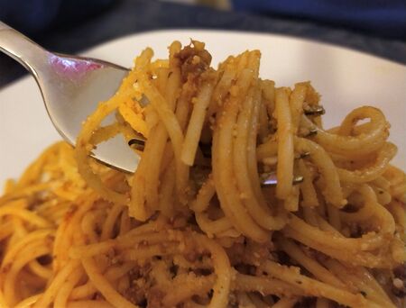 Italian spaghetti bolognese with cheese on a fork, close up. Traditional italian food ..