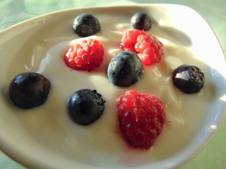 Yogurt and berries. Sour cream, yogurt in a bowl with fresh raspberries and black currants.の写真素材