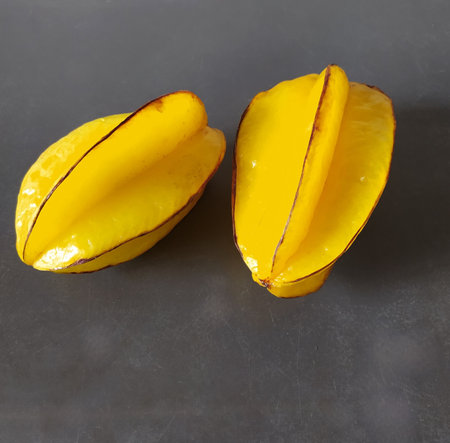 carambola fruit, isolated, close-up. two fresh ripe whole yellow fruits on a gray table background.の写真素材