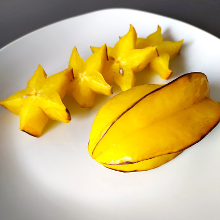 Carambola fruit, isolated, close-up. Fresh ripe yellow fruits of Averrhoa carambola, one fruit is whole and the other is sliced. Sliced star fruit on a plate, background.の写真素材