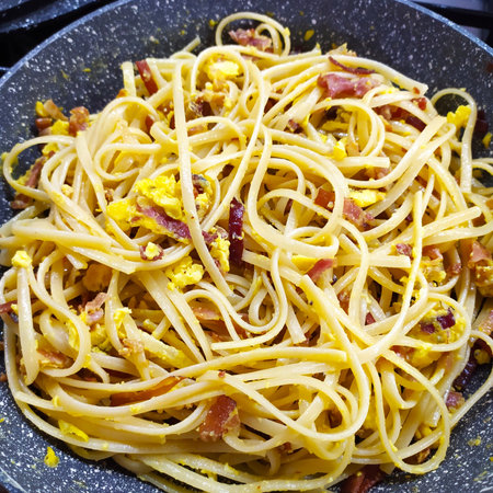Carbonara pasta with bacon, egg, parmesan cheese and cream sauce. Homemade, close-up. Spaghetti carbonara with bacon and egg in a black pan. Italian cuisineの写真素材