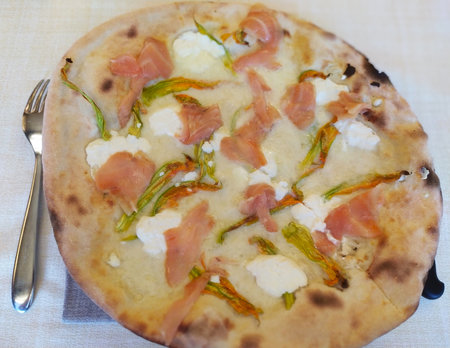 Pizza with salmon, courgette flowers and cheese, close-up. Italian white pizza with salmon, zucchini flowers and mozzarella cheese.の写真素材