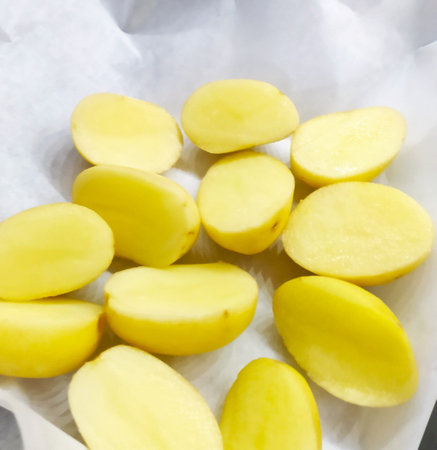 Sliced potatoes on a white background. Close-up. peeled and sliced raw potatoes on baking paper. baked potato cooking process. home made.の写真素材