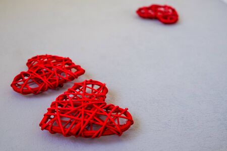Three red figures of the heart of rattan as a symbol of love and Valentine's Day on a gray surface....