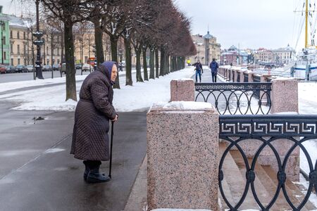 Russia, St. Petersburg. February 09, 2020. An old woman stands and looks forward for a walk in winter, early spring. Old age, lonely old age concept. Horizontal orientation.のeditorial素材